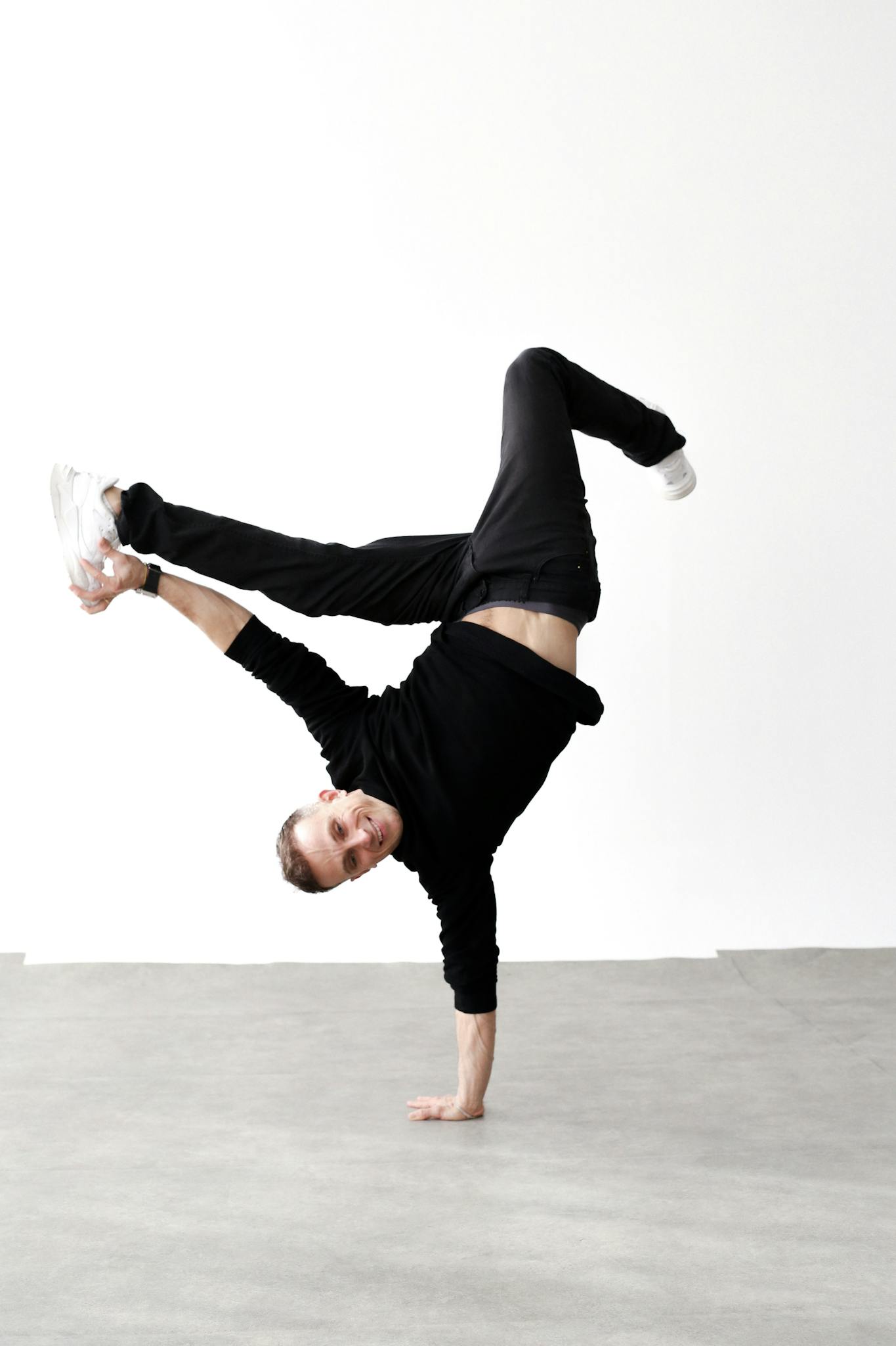 A skilled breakdancer executing a handstand move in an urban setting in Berlin.